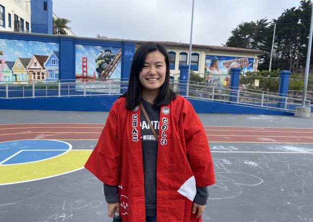 Megumi Matsuno, SFUSD Alum poses in front of Rosa Parks Elementary School