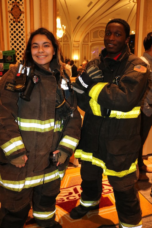 Two students try on firefighter gear as part of a career exploration event. 