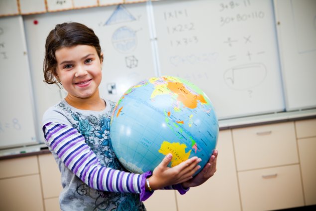 Girl holding globe in classroom