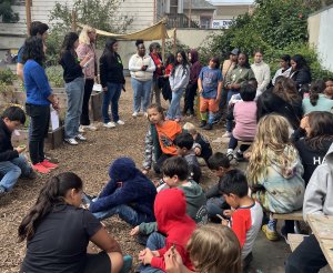 Room 301, 302, 303 students sitting in the garden with Sandcastle volunteer team