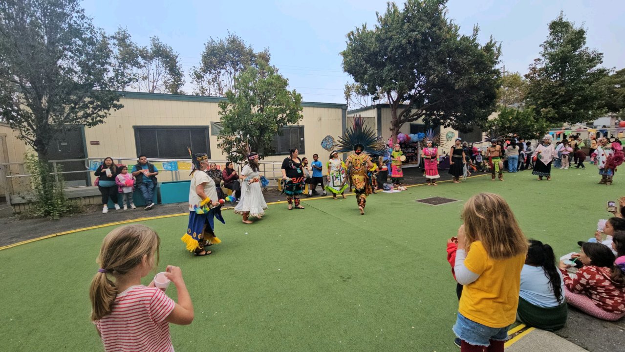 Azteca group dancing in the yard wearing traditional garments