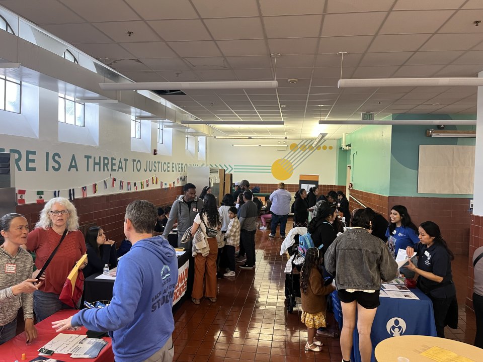 Parents talking to community partners at Resource Tables, with Superintendent Wayne in the foreground