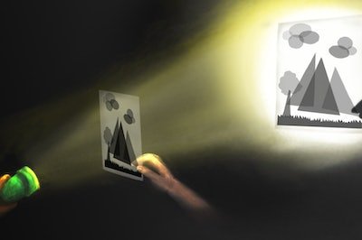 flashlight projecting light on mountain cutout to cast a shadow