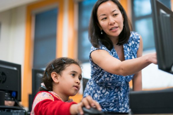 Teacher helping a young student learn on a computer