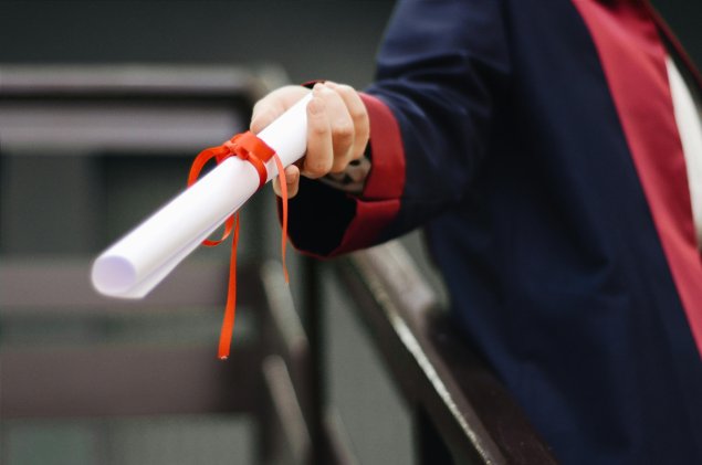 Person wearing graduation gown holding diploma