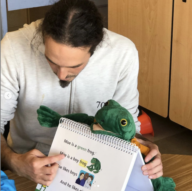 Teacher with frog puppet reading to his class